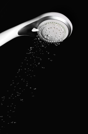 Modern shower head with running water isolated on black backgroundの写真素材