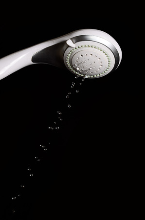 Modern shower head with running water isolated on black backgroundの写真素材