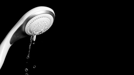 Modern shower head with running water isolated on black backgroundの写真素材
