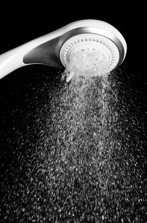 Modern shower head with running water isolated on black backgroundの写真素材