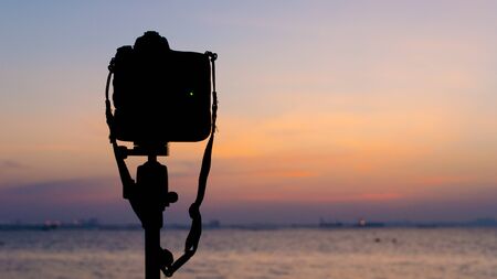 Silhouette of DSLR camera at sea with sunset skyの写真素材