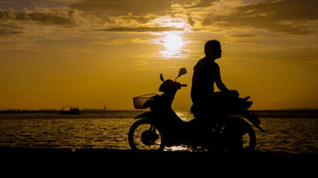 Silhouette of man sit on motorbike for see sunset skyの写真素材