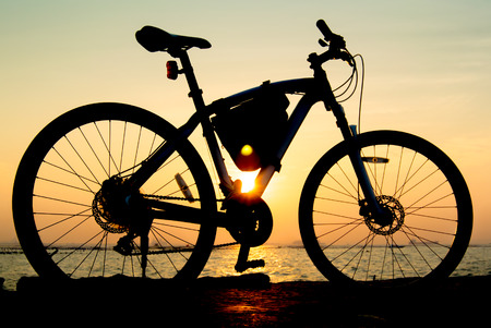 Silhouette of mountain bike at sea with sunset sky backgroundの写真素材