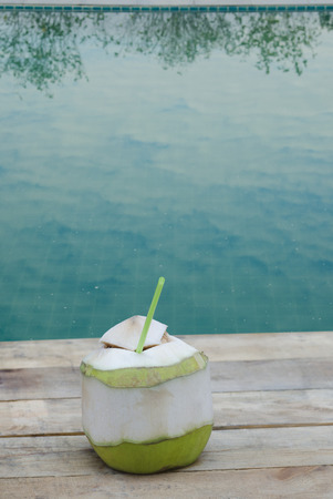 Coconut drink on wooden table at swimming poolの写真素材