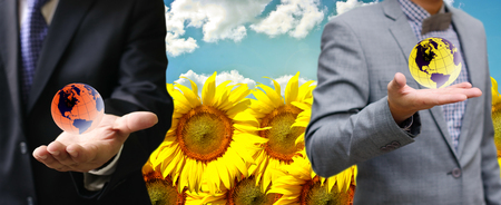Businessman carry the world in hand with sunflowers filed backgroundの写真素材