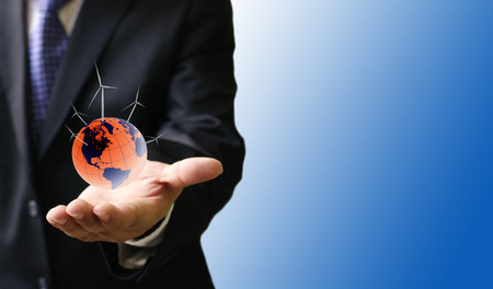 Sustainable energy concept, World with wind turbine in businessman handの写真素材