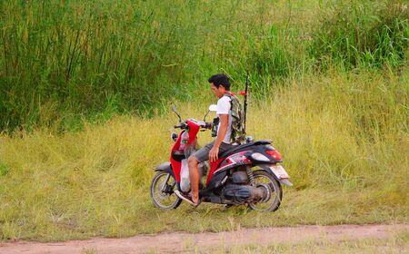 CHONBURI, THAILAND - 11 OCT : Unidentified man with fishing rod parking motorcycle at field on 11 October 2019 in Bangpra, Sriracha, Chonburi, Thailandのeditorial素材