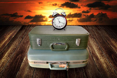 Time to travel concept, Alarm clock on vintage travel bag with sky backgroundの写真素材