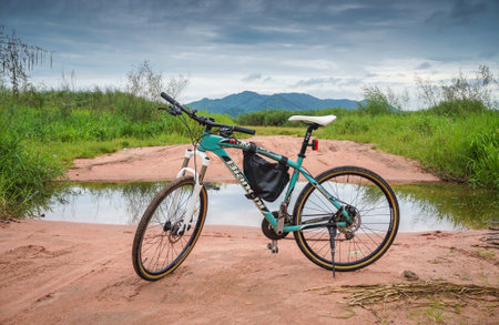 CHONBURI; THAILAND - 28 SEP : Mountain bike parking at clay road before pond with mountain...