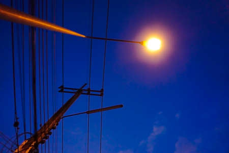 Light from street light and silhouette of electric pole with night sky background