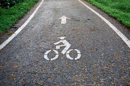 Bike lane symbol on road with green area aroundの写真素材