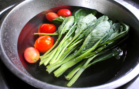 Fresh vegetables washed in sinkの写真素材