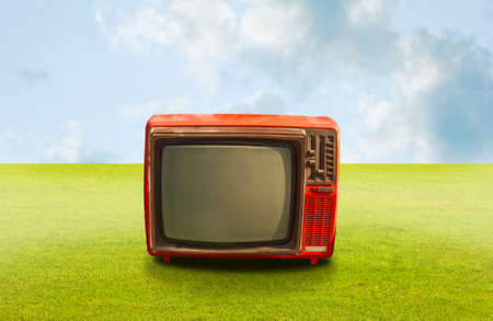 Vintage television on grass with clouds sky backgorundの写真素材