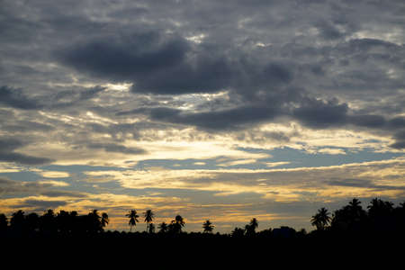 View of sunset ray with clouds in sky and silhouette of landscape foregroundの写真素材