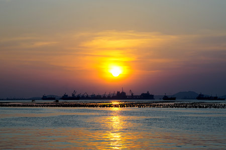 Sunset sky at sea with silhouette of island and cargo ship backgroundの写真素材