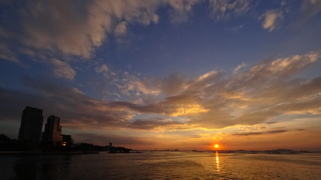 Sunset sky at sea with silhouette of tower at bankの写真素材