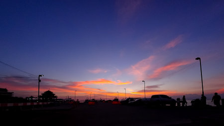 Dramatic sky with silhouette of street lamp and car parkの写真素材
