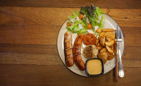 German sausage grilled with salad and potato chips, Top view with wooden table backgroundの写真素材