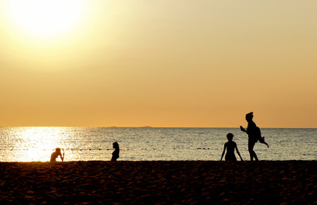 Silhouette of people relax on beach with sunset sky backgroundの写真素材