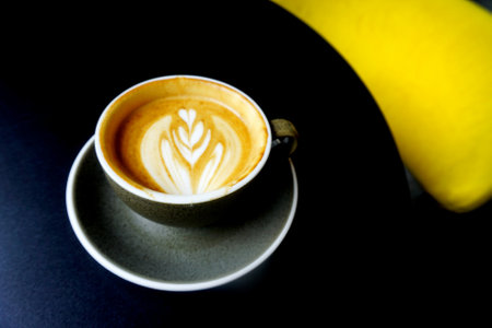 Drinking hot latte coffee, Close up shot of hot coffee cup on black tableの写真素材