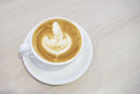 Milk coffee with latte art, Hot coffee on wooden tableの写真素材