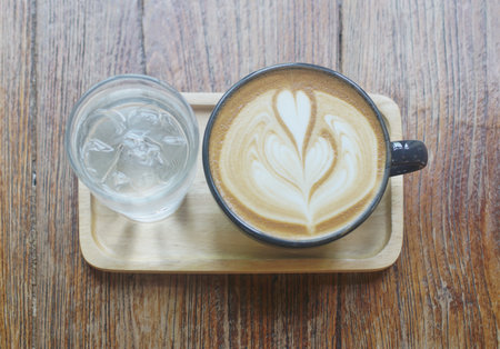 Latte coffee and fresh drinking water on wooden trayの写真素材