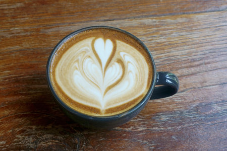 Coffee cup with latte art on wooden tableの写真素材
