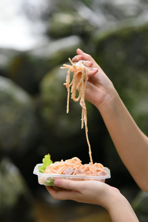 Lunch box with Spaghetti with woman hand holding fork and lift upの写真素材