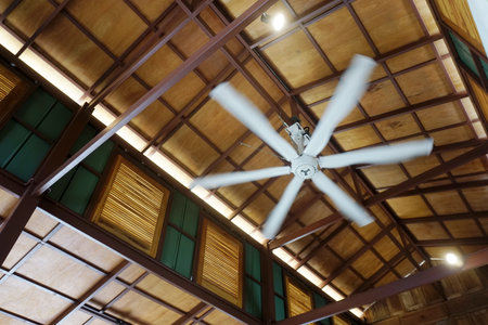 Big fan with motion blur at high ceiling with wooden window besideの写真素材