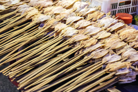 dry squid are pierce by bamboo stick in street market , Thailand