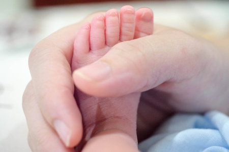 Tiny Newborn Baby 's Foot On Female Hands , Closeup.の写真素材