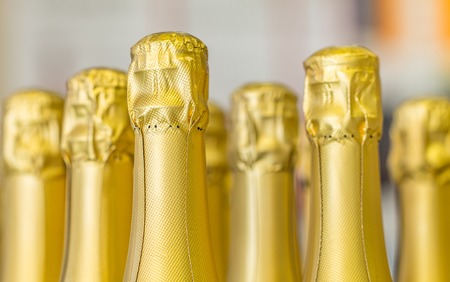 Big amount of golden champagne bottles necks and top caps at standing the light background.の写真素材