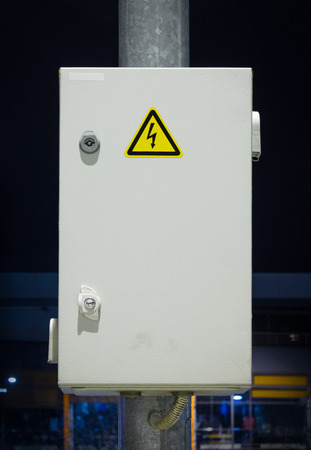 Control electric box on dark background at night attached to a pole.
