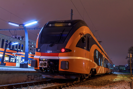New modern orange train at night, photos from the side. Empty station without anybody standing on the platform. European transport electricity.の写真素材