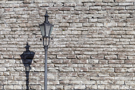 Retro rustic lamppost with lantern on it in front of old stone ancient wall in Old Tallinn, Estoniaの写真素材