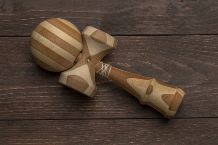 Brown kendama laying on a dark wooden rustic background. Traditional japanese toy. Accuracy and agility development. Kids, children, ball game.の写真素材
