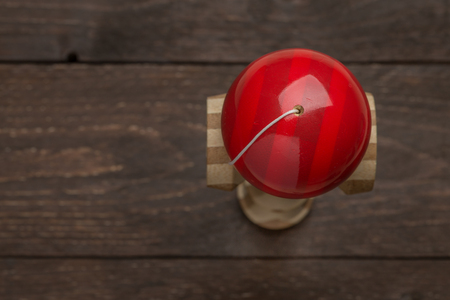 Red kendama standing on a dark wooden rustic background. Traditional japanese toy. Accuracy and agility development. Kids, children, ball game.の写真素材