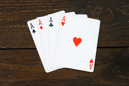 Aces of playing cards on old wood table concept of poker game texas. Four of a kind aces. Wooden background casino luck.の写真素材