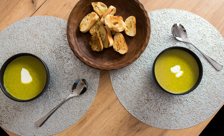 Green broccoli & spinach vegetable soup in black plate on wooden table.