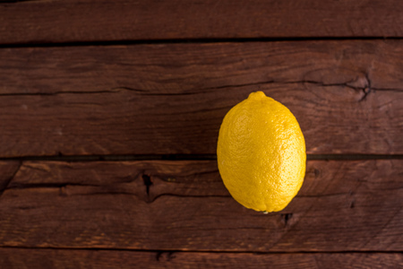 Single yellow lemon on brown oak wooden boards. Warm colors, natural light.の写真素材