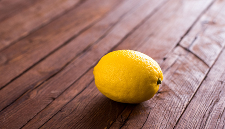 Single yellow lemon on brown oak wooden boards. Warm colors, natural light.の写真素材