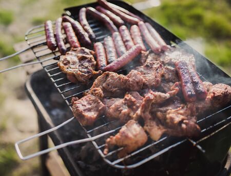 Grilling sausages on barbecue grill. Pork sausage and steak in smoke. Close-up view & Selective focus.の写真素材
