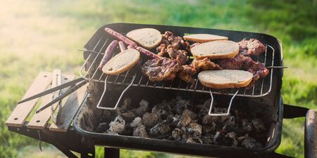 Grilling sausages on barbecue grill. Pork sausage and steak in smoke. Close-up view & Selective focus.の写真素材
