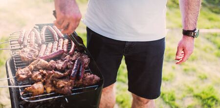 Grilling sausages on barbecue grill. Pork sausage and steak in smoke. Close-up view & Selective focus.の写真素材