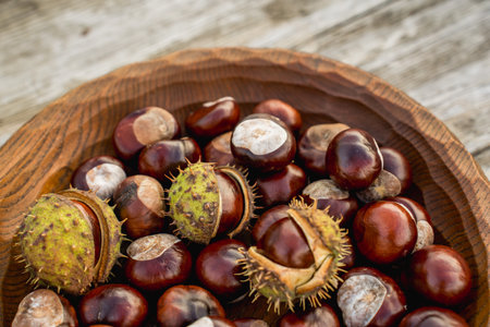 Chestnuts in a wooden bowl on a rustic wooden background.