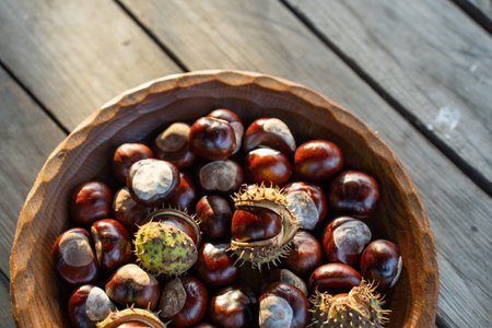 Chestnuts in a wooden bowl on a wooden table, top viewの写真素材