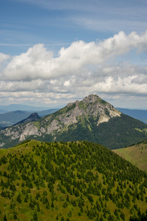 Mountain landscape with green forest and blue sky with white clouds.の写真素材