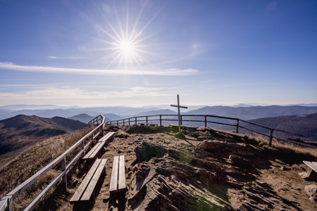 Wooden bench on the top of the mountain with blue sky and sunの写真素材