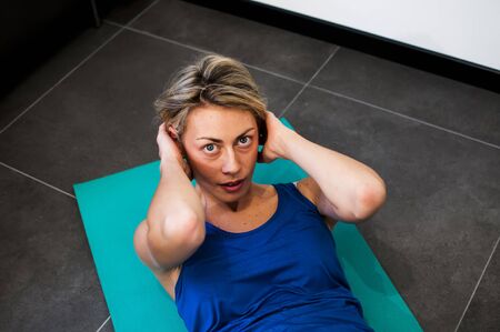 girl making fitness exercises, stretching, weight lifting and abdominalsの写真素材