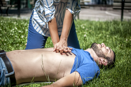 Girl making cardiopulmonary resuscitation to an unconscious guy after heart attackの写真素材